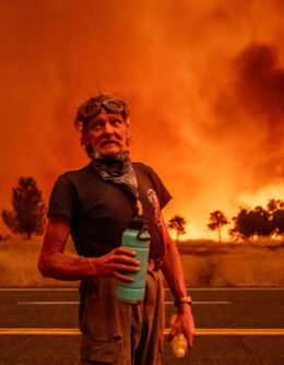 Grant Douglas pauses to drink water while evacuating as the Park Fire jumps Highway 36 near Paynes Creek in Tehama County, Calif., July 26, 2024. (AP Photo/Noah Berger)
